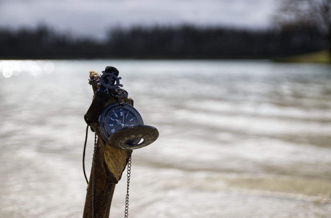 A compass and pocketwatch by water.